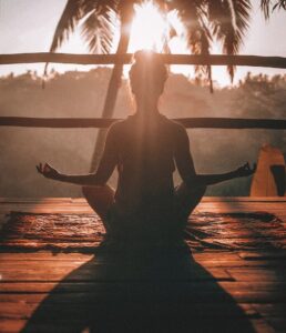 woman meditating on a balcony in the blog Why Self-Care Is Important And 6 Habits To Implement For A Healthy Lifestyle by Ritu Biswas