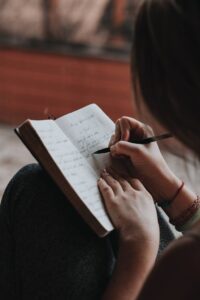 woman writing a journal in the blog Why Self-Care Is Important And 6 Habits To Implement For A Healthy Lifestyle by Ritu Biswas