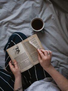 woman reading a book with a cup of coffee in the blog Why Self-Care Is Important And 6 Habits To Implement For A Healthy Lifestyle by Ritu Biswas