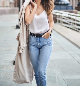Woman wearing white spaghetti top and mid rise jeans with long jacket in "6 ways to style spaghetti tops" Woman wearing white spaghetti top and mid rise jeans with long jacket in "6 ways to style spaghetti tops"